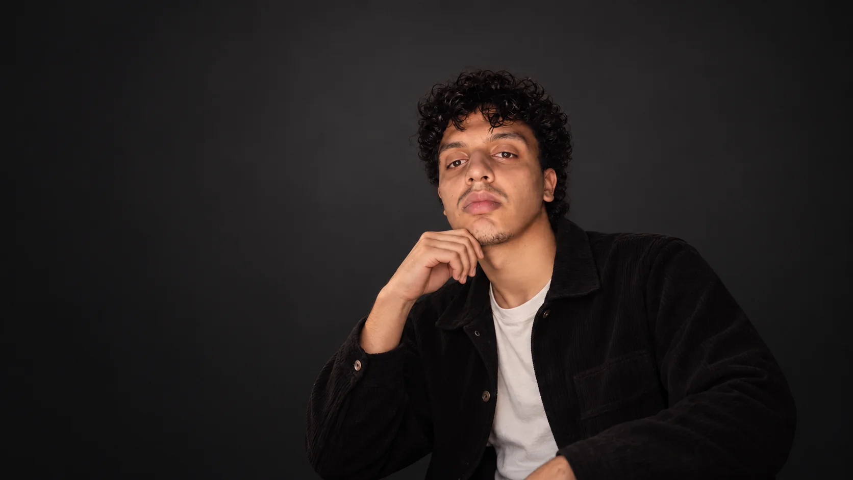 Portrait of Ayoub Ahajji against a clean charcoal studio background